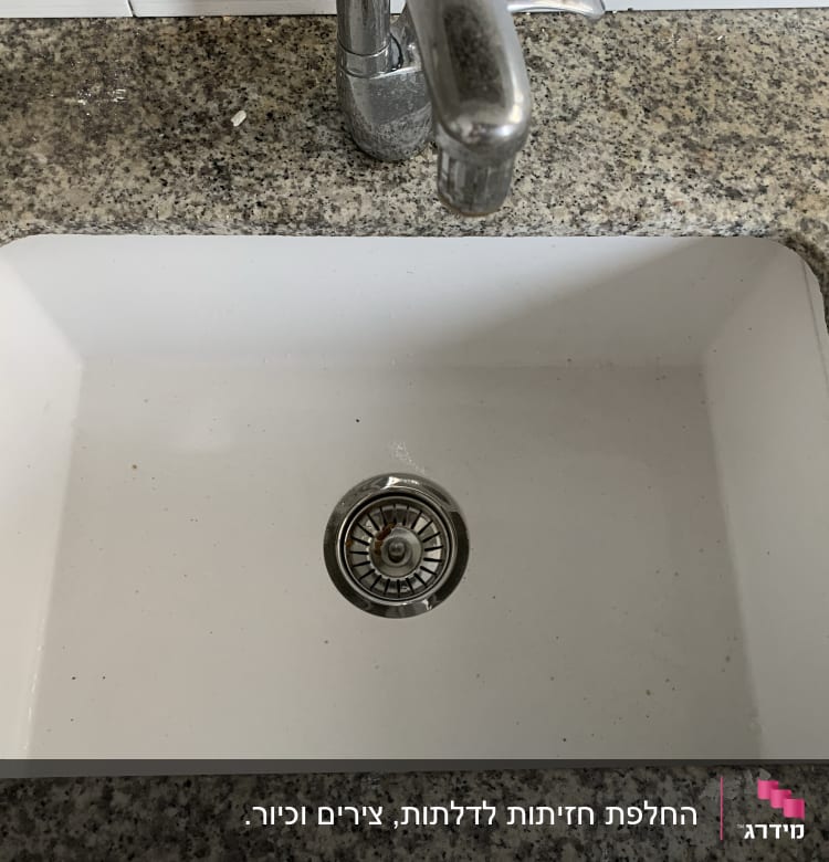 כיור מטבח לבן עם ברז מתכת על משטח גרניט